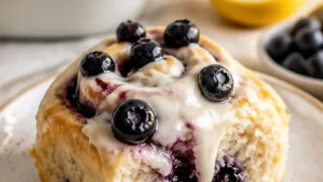 Zitronen-Blaubeer-Süßschnecken auf einem Backblech, frisch gebacken.