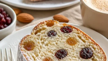 Schneebedeckter Christstollen mit getrockneten Früchten und Nüssen auf einem Tisch