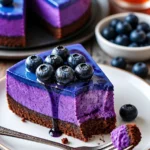 Mitternachts-Blaubeer-Käsekuchen auf einem Teller mit frischen Blaubeeren dekoriert.
