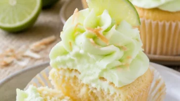 Kokos-Limetten-Cupcakes auf einem Tisch dekoriert mit Limettenscheiben