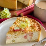 Rhabarber-Cheesecake mit knusprigem Crumble auf einem Teller serviert