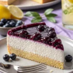 Schmandtorte mit Waldbeeren auf einem weißen Teller dekoriert