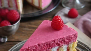Wickeltorte mit Himbeeren auf einem Teller, dekoriert mit frischen Himbeeren.