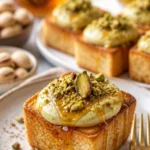Pistazien-Cheesecake-Toasts auf einem weißen Teller garniert mit frischen Pistazien.